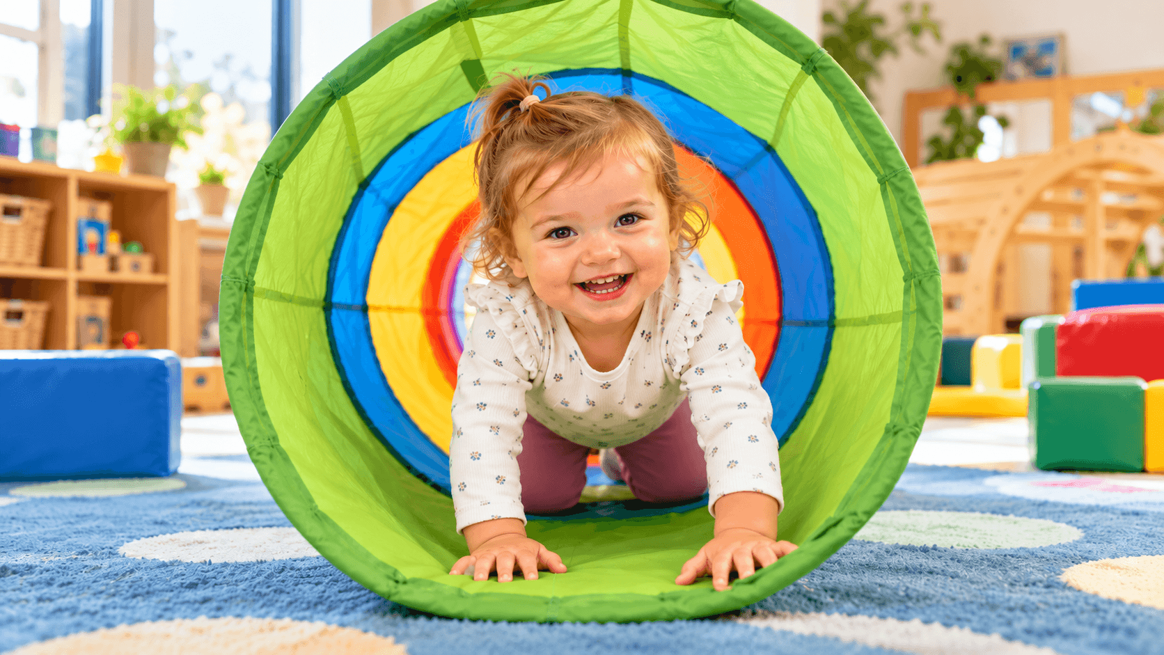 Toddler crawling through a fabric play tunnel, a movement that supports primitive reflexes and sensory development